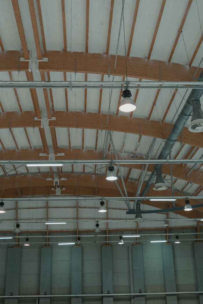 High-angle view of a spacious industrial ceiling featuring pendant lights and steel design elements.